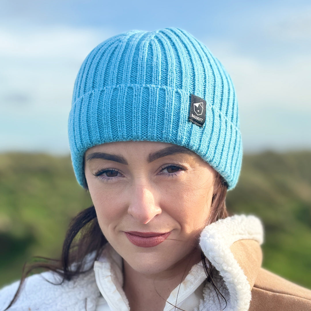 A aqua blue BAUMUTT fisherman beanie hat with a snug fit, designed for men and women. front view on female model
