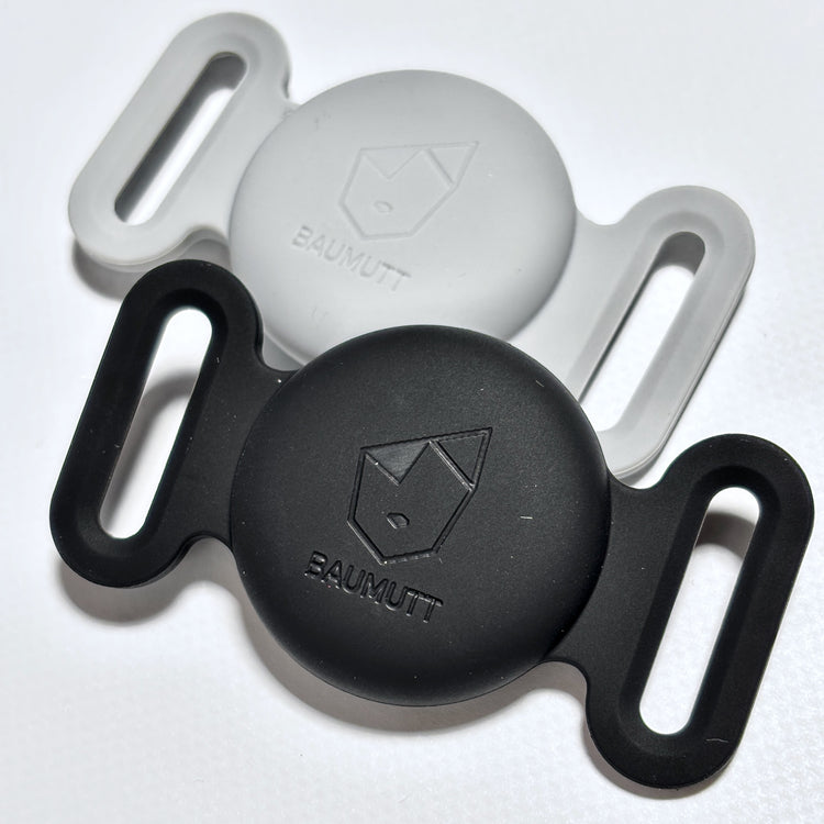 Two silicone Apple AirTags dog collar holders, one black and one gray, each with BAUMUTT logo on the front.