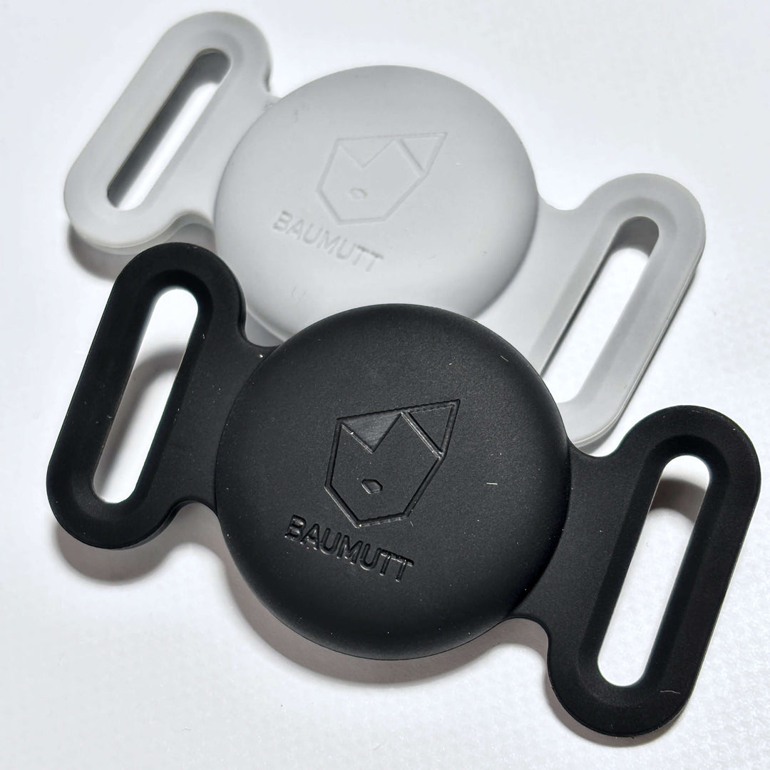 Two silicone Apple AirTag dog collar holder, one black and one gray, each with BAUMUTT logo on the front.